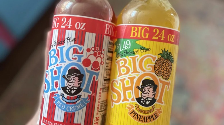 Hand holding bottles of Big Shot red creme and Big Shot pineapple