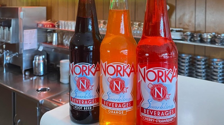 Three bottles of Norka on a counter in a commercial kitchen