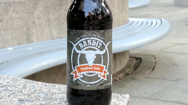 Bottle of IronPort soda sitting outside in front of a blurred bench