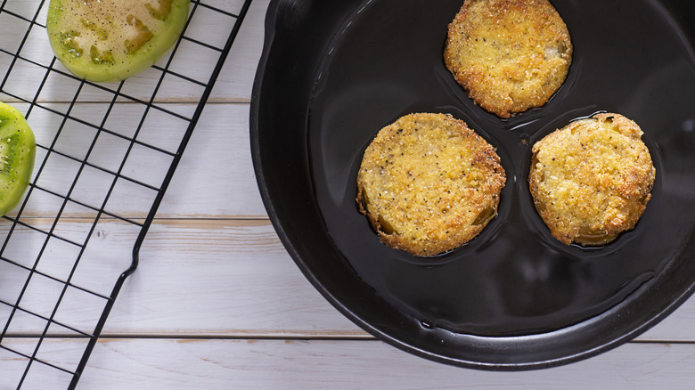 Fried green tomatoes in cast iron skillet on white table