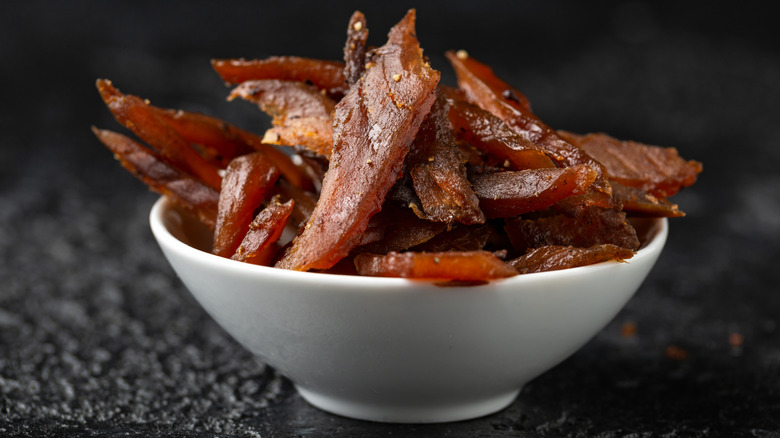 White bowl of smoked salmon jerky on black surface