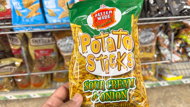 Hand holding bag of Better Made Potato Sticks