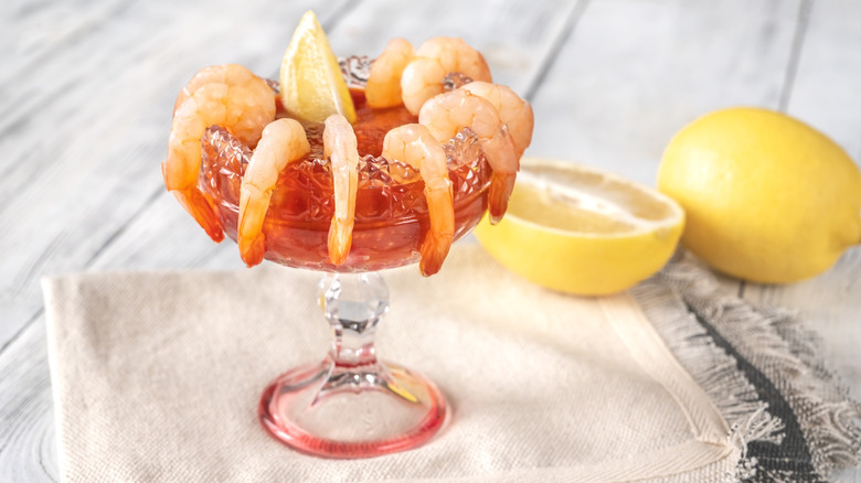 Shrimp cocktail next to lemon wedges on dish cloth