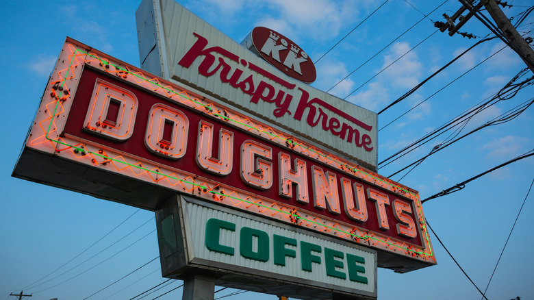 Neon Krispy Kreme Doughnuts sign in front of blue sky