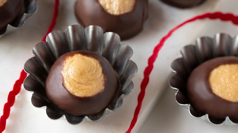 Buckeye candies in small tins on white tablecloth