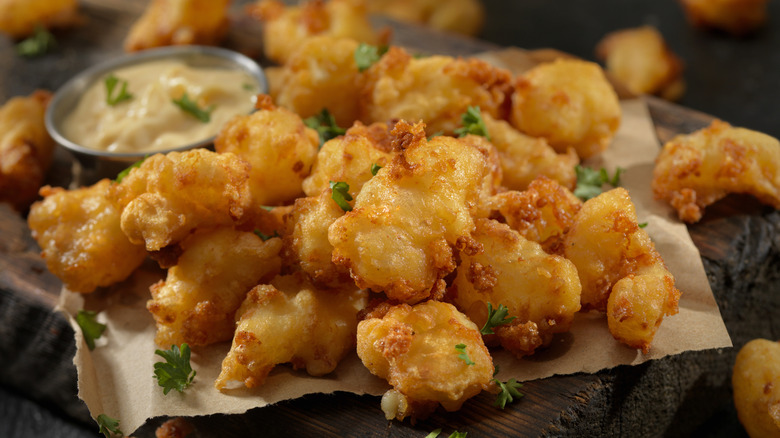 Pile of fried cheese curds next to dipping sauce