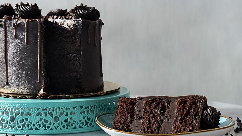 For the Love of Sugar Matilda chocolate cake on a cake stand with one slice on a plate
