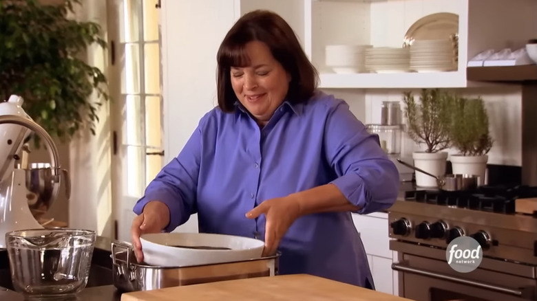 Ina Garten putting a dish in a water bath in the kitchen on the set of Barefoot Contessa