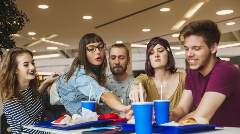 Group of teens hanging out and eating at a mall food court