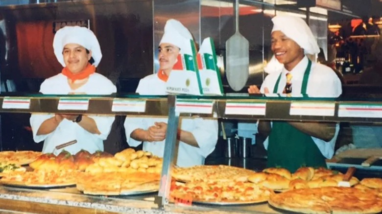 Three people standing behind a Sbarro pizza counter