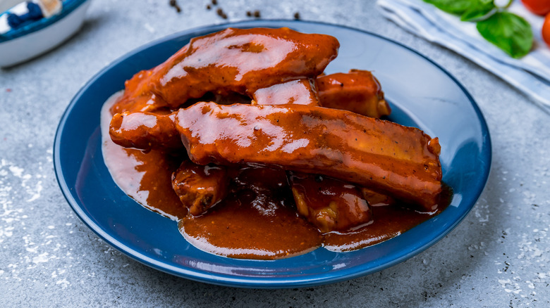 Blue plate of pork ribs smothered in barbecue sauce