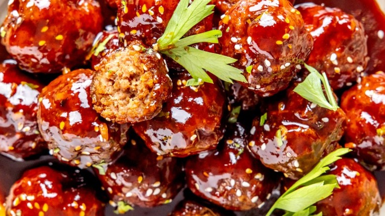 Meatballs in a sweet and spicy glaze, topped with herbs and sesame seeds