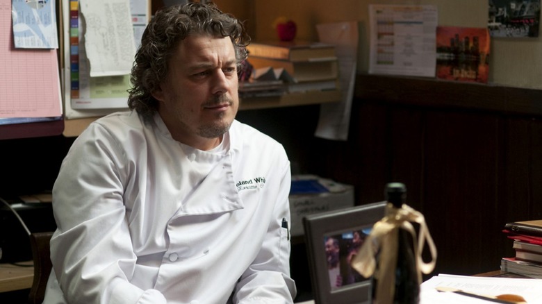 Chef Roland White smirking while sitting in his office in a still from "Whites"