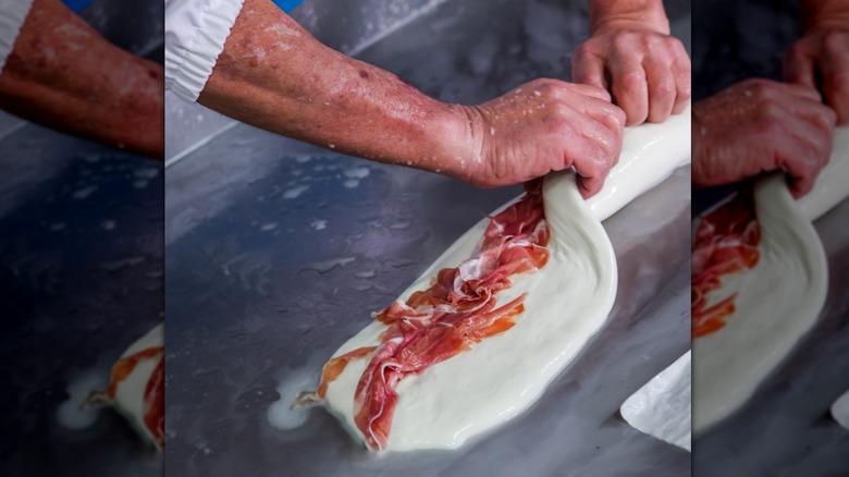 Folding sheet of mozzarella over filling of cured meat