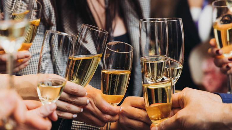 People holding up sparkling wine glasses at a party