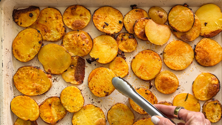 tongs flipping potato slice on sheet pan