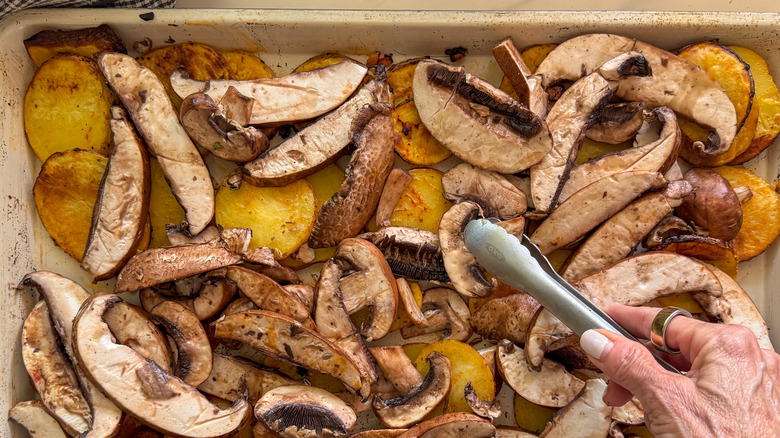 Tongs placing mushroom slice on sheet pan