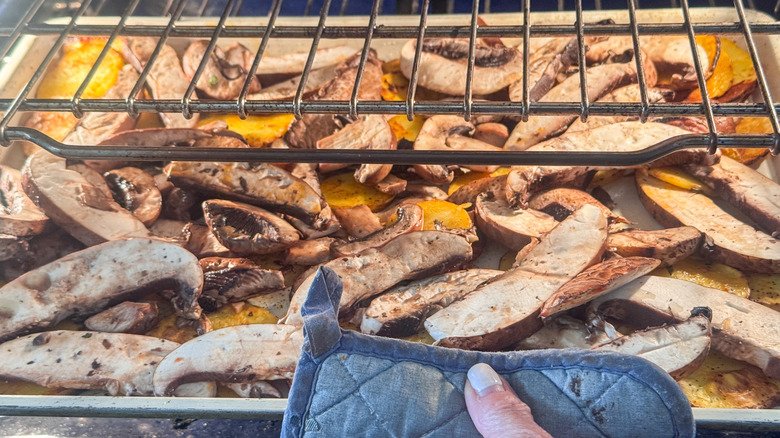 Placing sheet pan with potatoes and mushrooms into oven