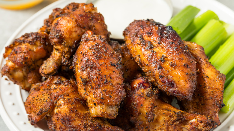 A closeup of seasoned chicken wings with celery