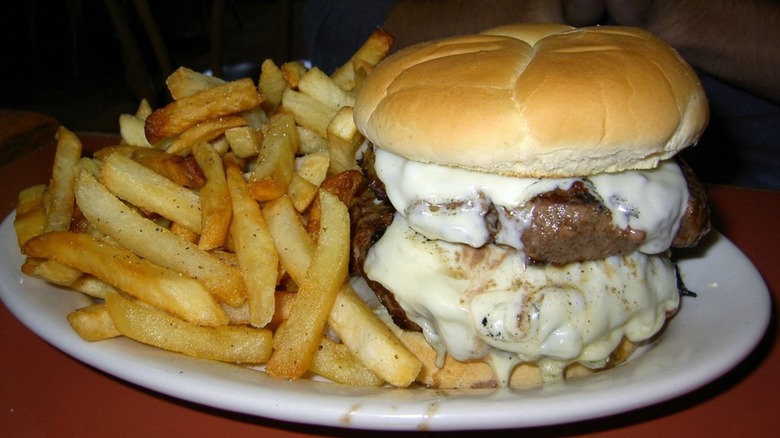 Double burger with melty cheese on plate with fries