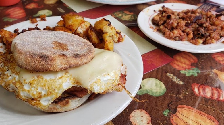 English muffin breakfast sandwich and plate of hash