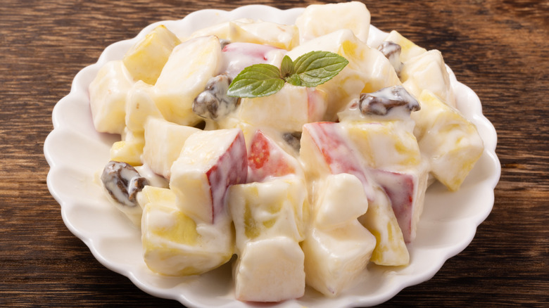 A white bowl of potato, raisin, and apple salad