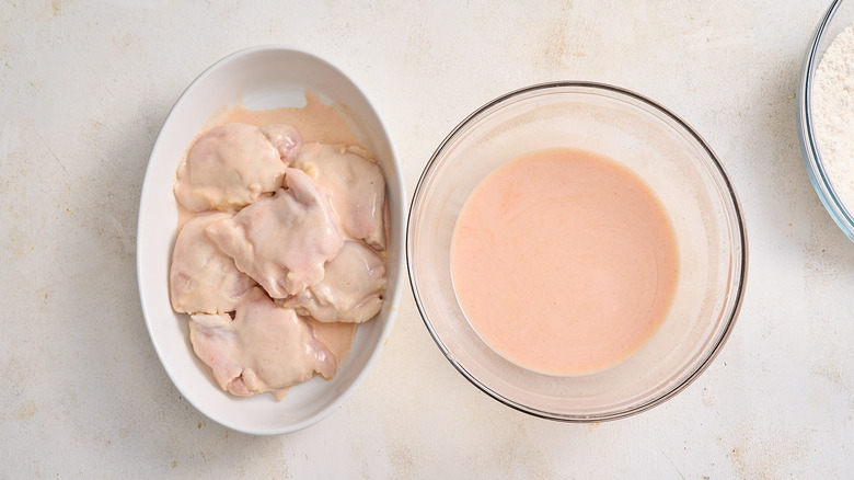 marinated chicken in bowl next to leftover marinade in separate bowl