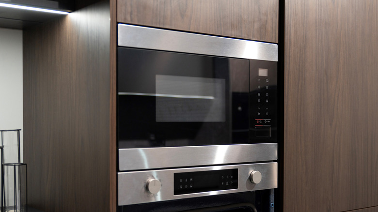 Built in, wall-mount microwave and wall oven combination in a kitchen with dark wood cabinetry