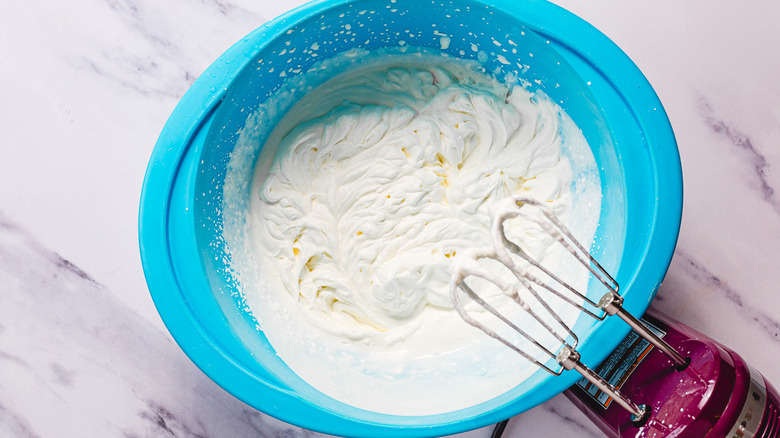 Whipped cream in bowl with hand mixer
