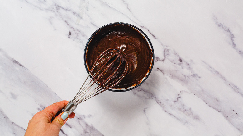 Whisking melted chocolate and condensed milk in bowl