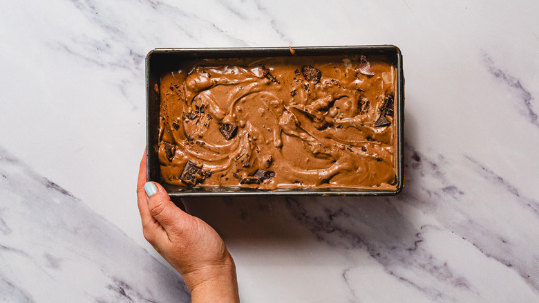 Hand holding chocolate ice cream in container