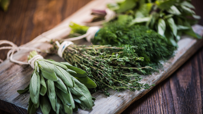 a wide wooden board holding bunches of various green herbs