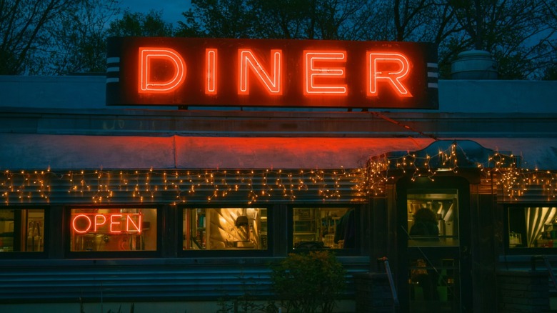 A diner with red neon signs illuminated at night