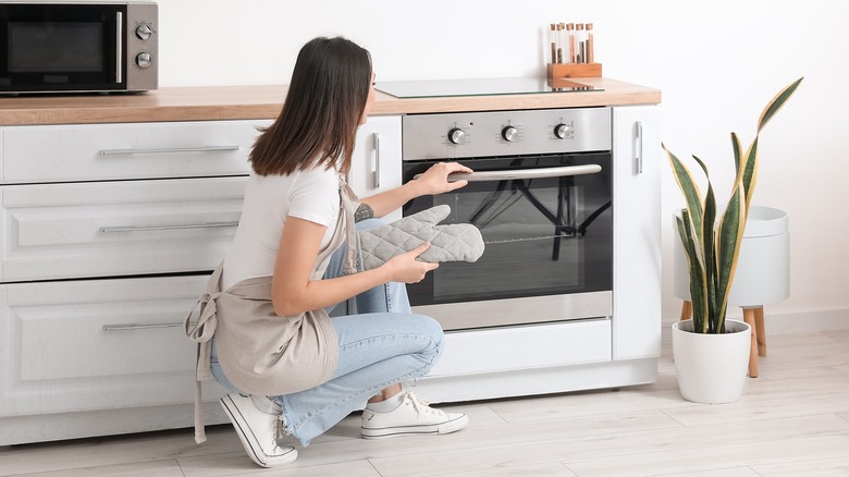 Woman kneeling near oven