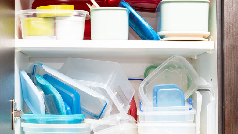 Messy cupboard full of plastic containers and lids