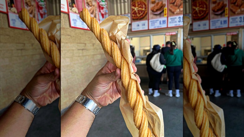 Hand holding Costco foot long twisted churro at outdoor Costco food court