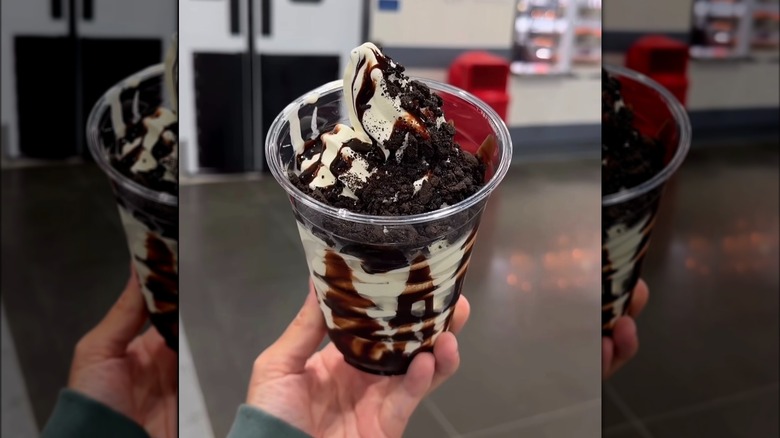 Hand holding Costco food court Vanilla Cookie Crunch Sundae with chocolate sauce