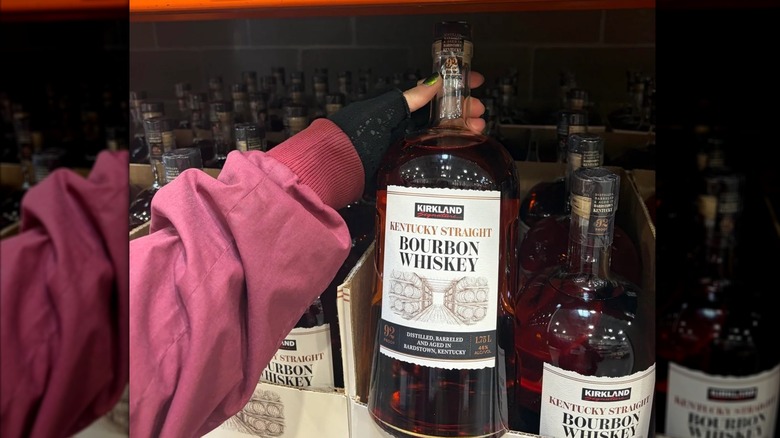 person holding bottle of Kirkland Signature Kentucky Straight Bourbon Whiskey at Costco