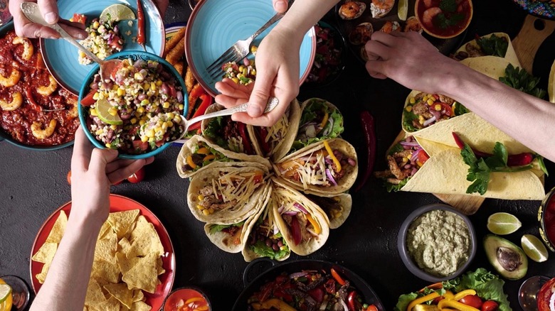 Top-down view of hands serving various Mexican dishes