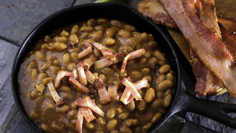 Southern baked beans are cooked in a cast iron skillet with bacon.