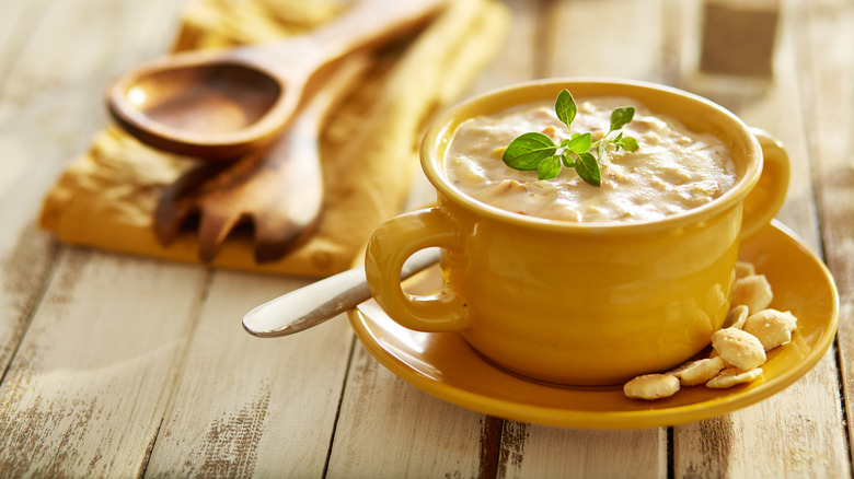 Steamy mug of New England clam chowder with spoon and bread up close