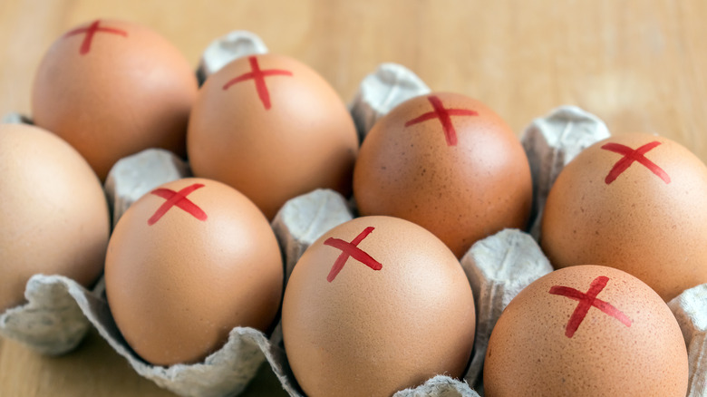 Dozen brown eggs with red x's across the top