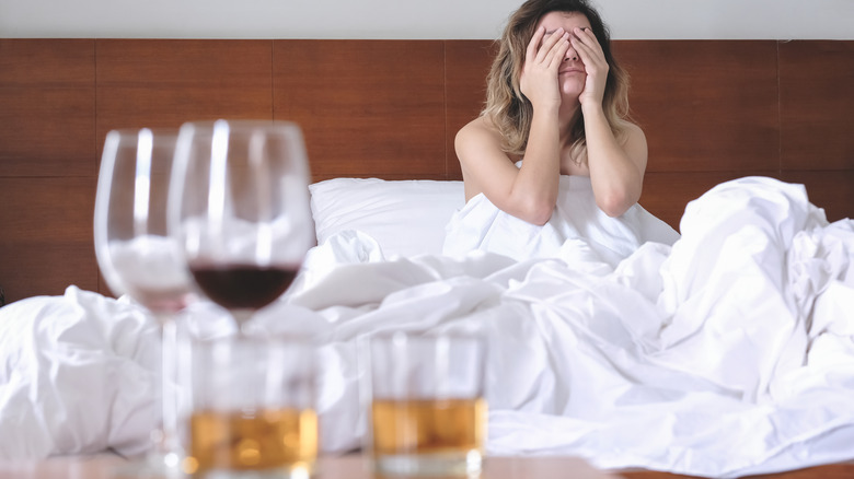 unfinshed drinks on table in front of person with headache in bed