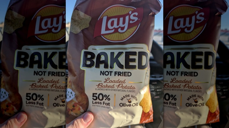 Hand holding bag of Baked Lay's Loaded Baked Potato Chips
