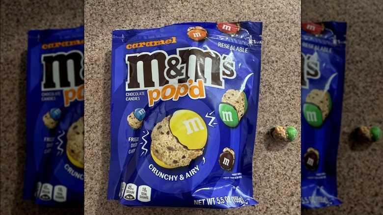Bag of M&M's Pop'd Caramel on a countertop next to a piece of candy