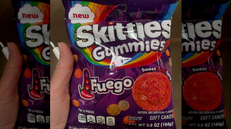Hand holding a bag of Skittles Gummies Fuego