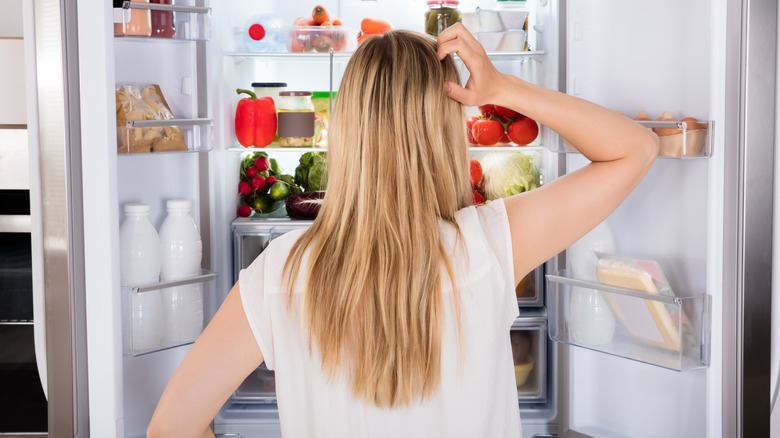 confused woman looking in refrigerator