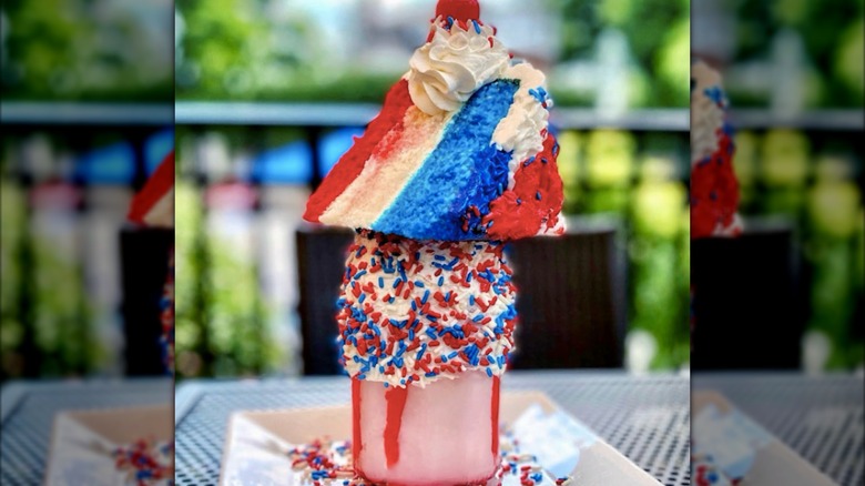 Festive milkshake with a slice of cake on top, colored red, white, and blue