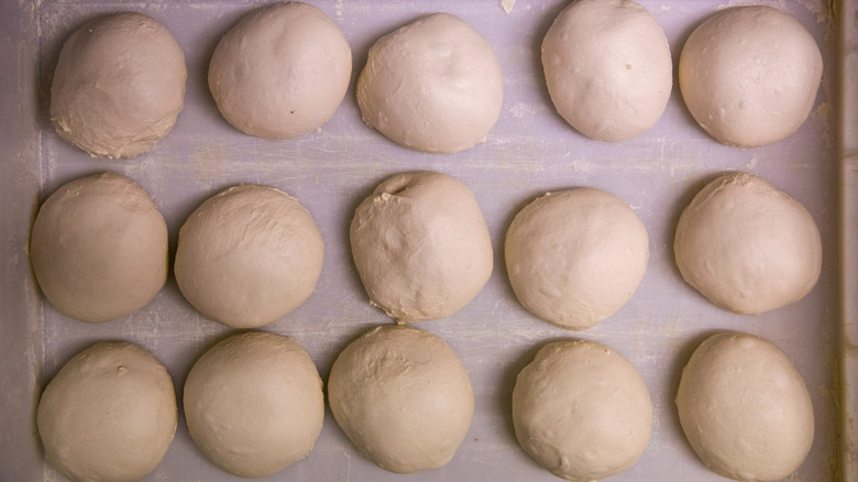 balls of pizza dough resting on sheet pan