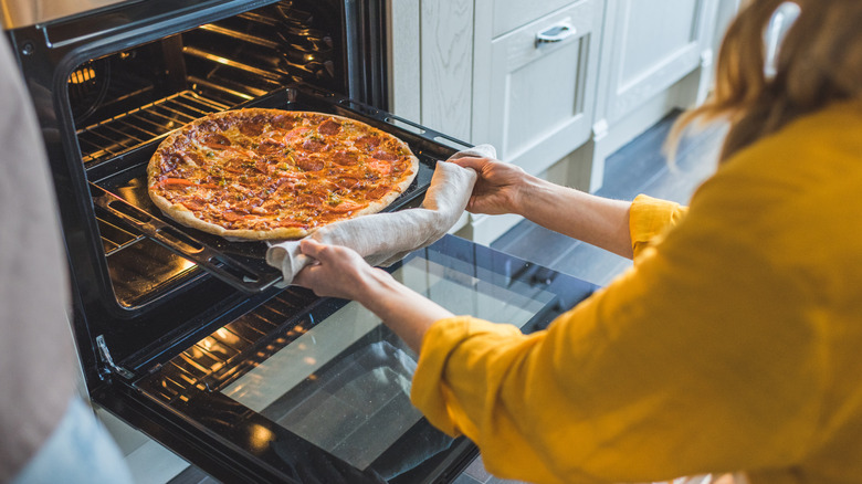 taking pizza out of the oven
